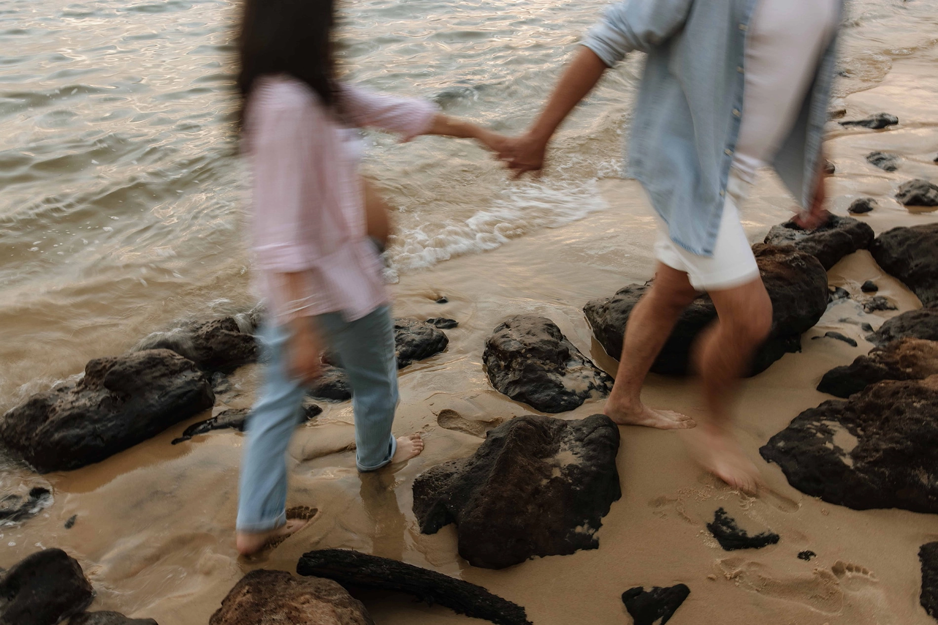 Un couple qui marche main dans la main au bord de l'eau.