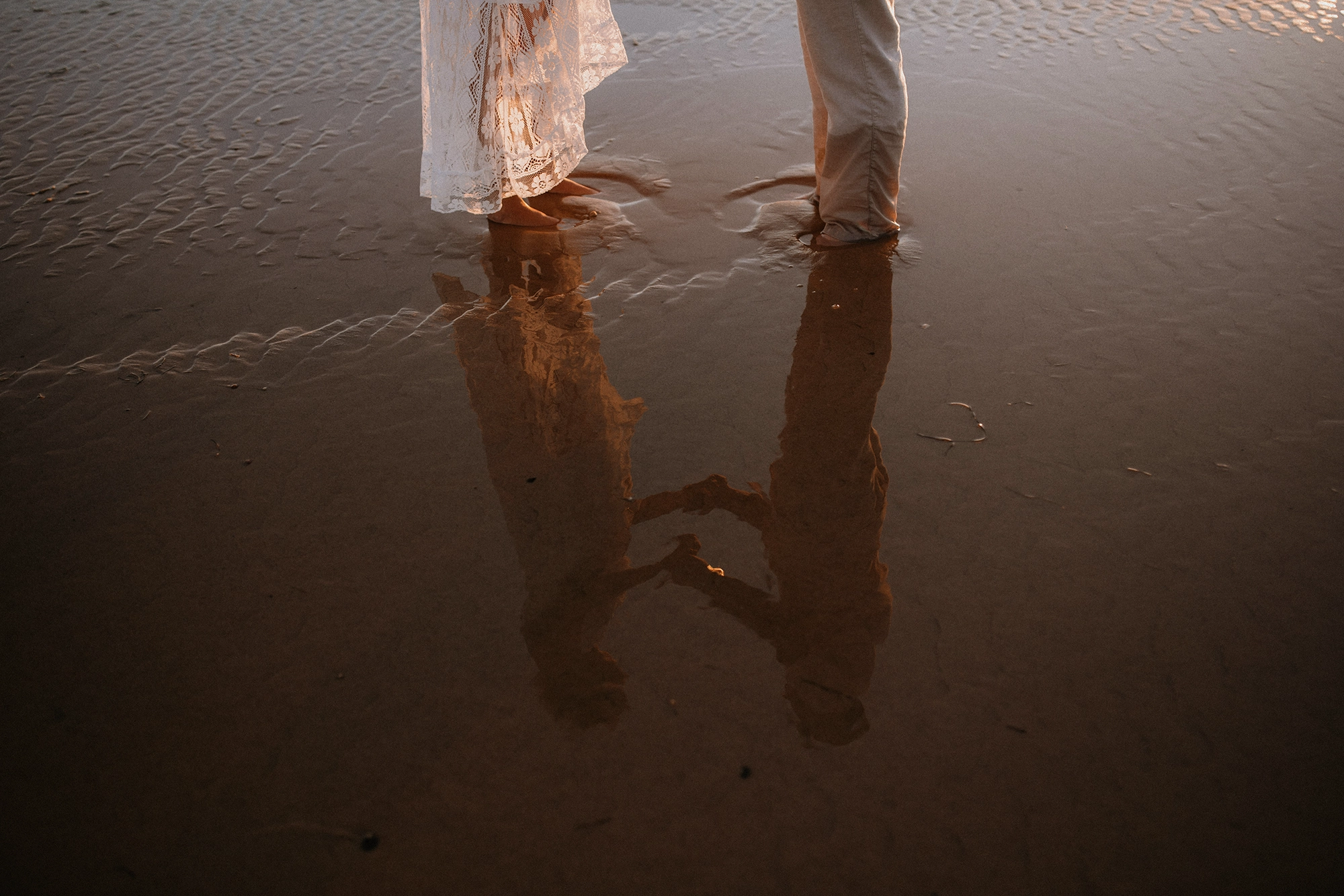 Reflet dans l'eau d'un couple qui se tient la main.