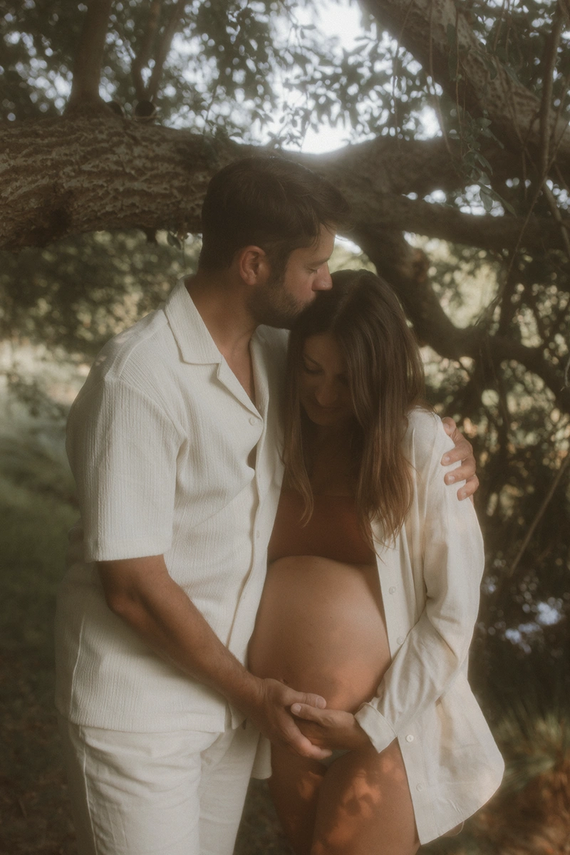 Un couple se prend dans les bras et la femme est enceinte.