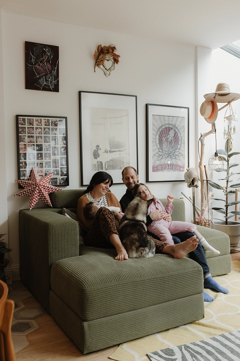 Une famille réunit sur la canapé du salon avec leur chien.