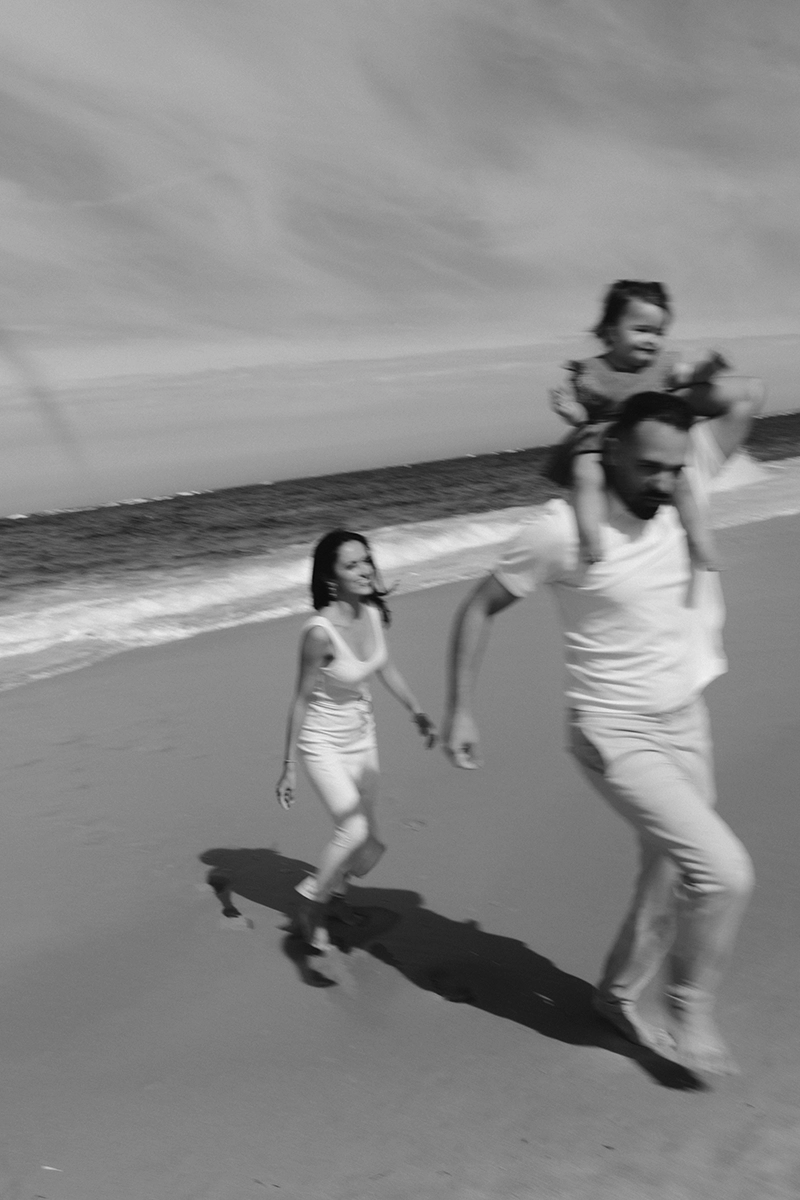 Des parents jouent avec leur petite fille sur la plage.