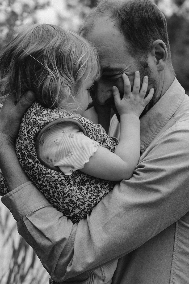 Un père et sa fille sont front contre front et se font un câlin.