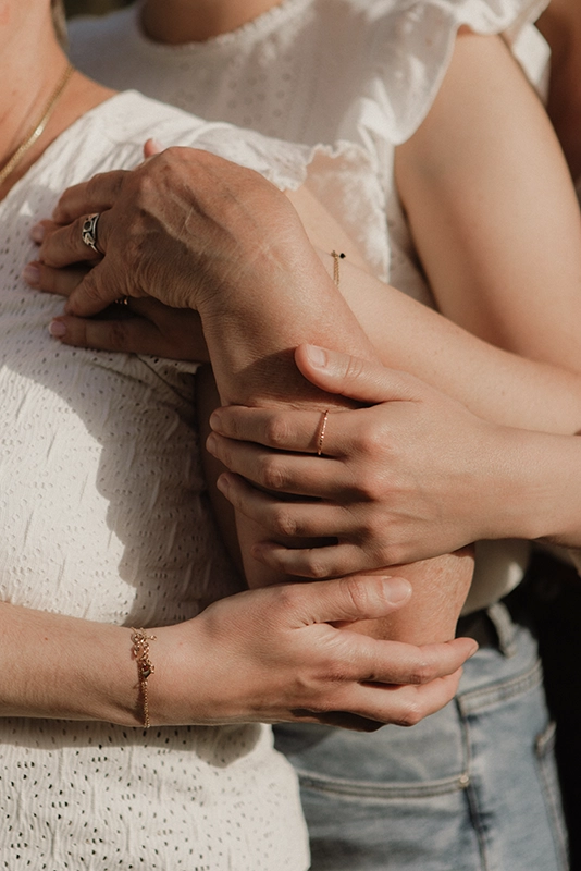 Trois filles posent une de leur main sur le bras de leur mère.