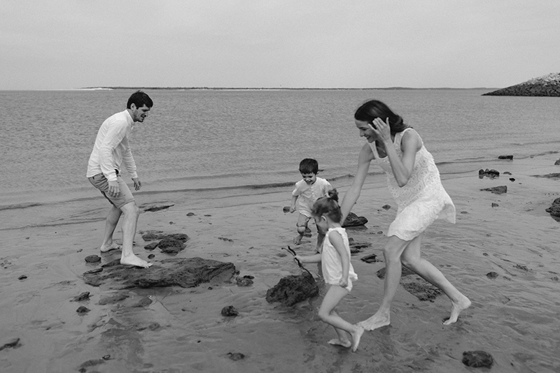 Une famille joue avec leurs enfants au bord de l'eau.