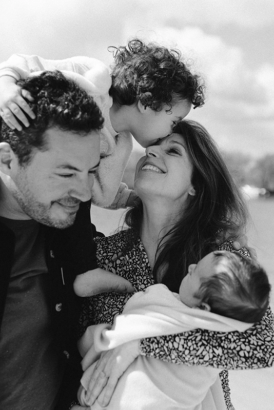 Une petite fille fait un bisous sur le front de sa mère, portée par son père.