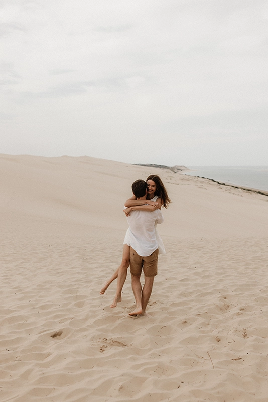 Un couple se prend dans les bras et tourne dans le sable.