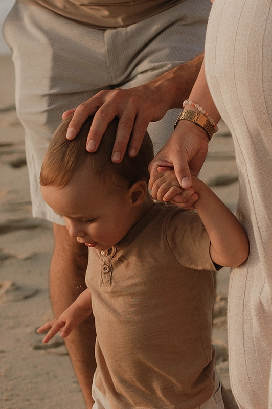 Des parents tiennent la main de leur enfant.